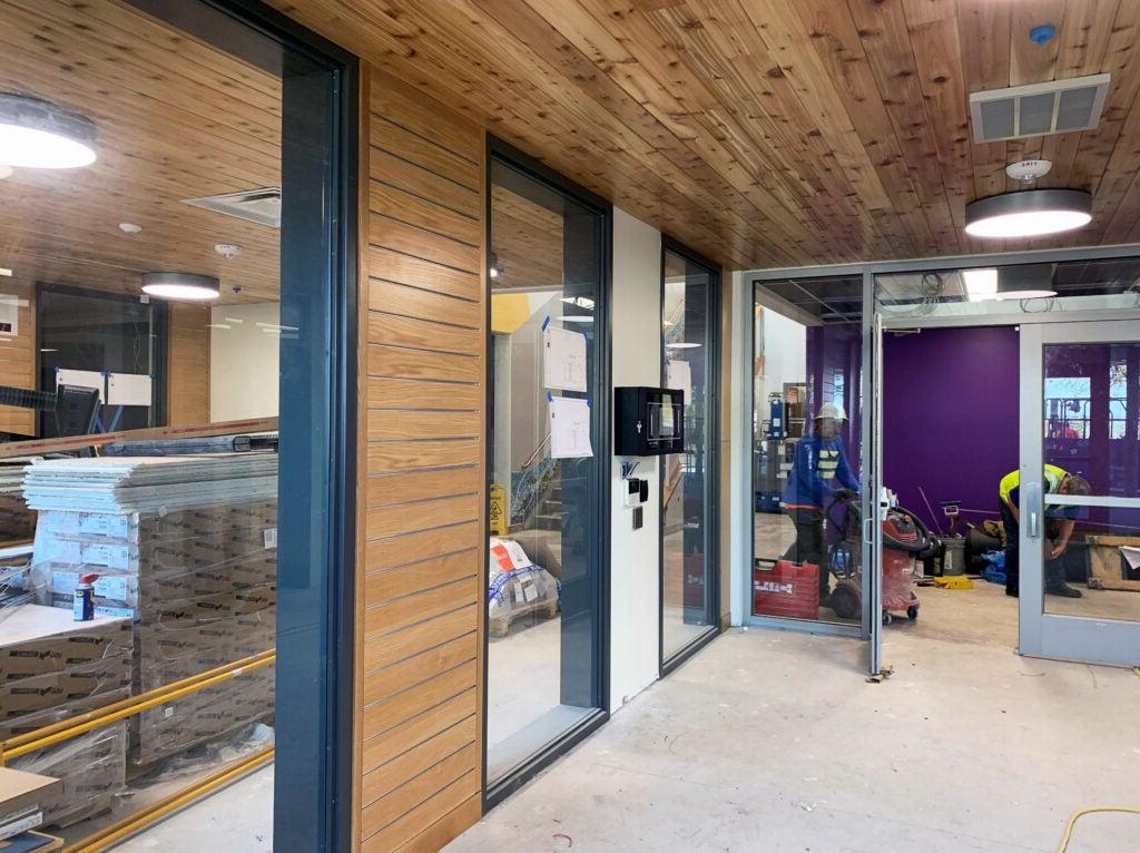 a section of a hallway with wood walls, windows on one side, and a door straight ahead